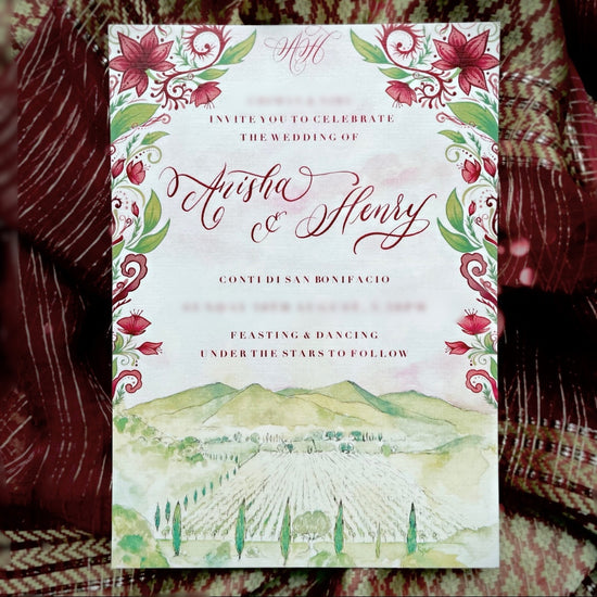 Watercolour wedding invitation. Illustrated Italian landscape with a bold floral border, calligraphy monogram, hand painted floral border, printed on textured card